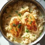 "Overhead view of creamy smothered chicken and rice on a clean white marble countertop, garnished with parsley flakes."