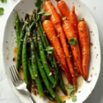 "Overhead shot of honey glazed carrots and green beans on a white platter"