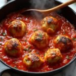 "Turkey meatballs in tomato sauce simmering in a skillet on a marble countertop"