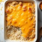 "Overhead shot of golden, bubbly chicken and rice casserole in a white ceramic dish on a marble background"