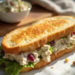 "Toasted chicken salad sandwich with grapes, celery, pecans on a clean white marble background"