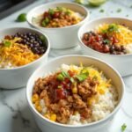"High protein burrito bowls with ground turkey, rice, black beans, corn, cheese, and salsa on a white countertop"