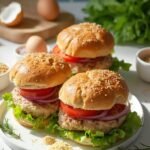 "Four delicious homemade turkey burgers on toasted brioche buns with lettuce, tomato and onion on a white ceramic plate in a modern kitchen"